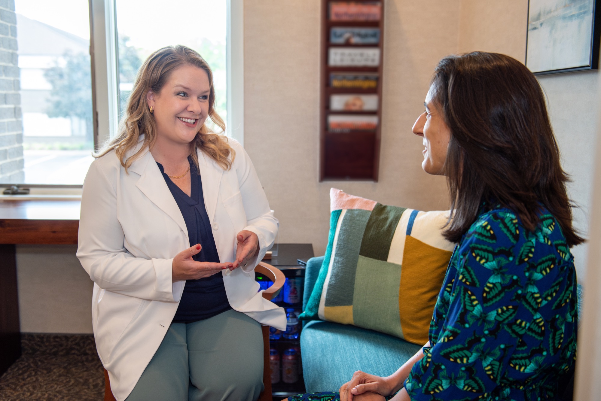 Dr. Julia Lokitis in conversation with a patient seated on the sofa in the waiting area at the Vienna office