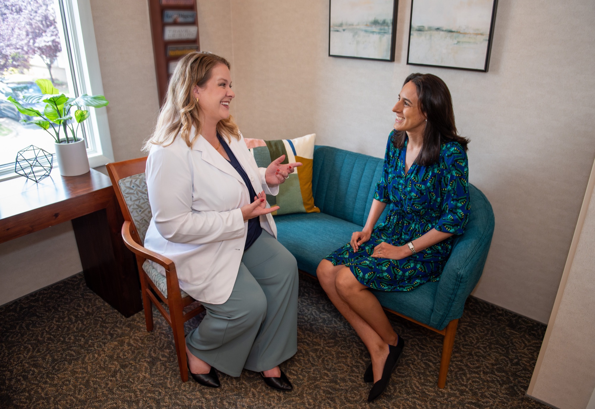 Dr. Julia Lokitis seated in the waiting area, talking with a patient on the sofa by the window