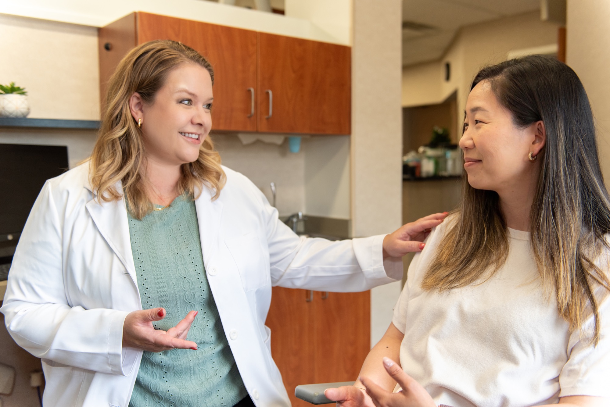 Dr. Julia Lokitis resting a hand on a patient's shoulder as they talk together in the treatment room