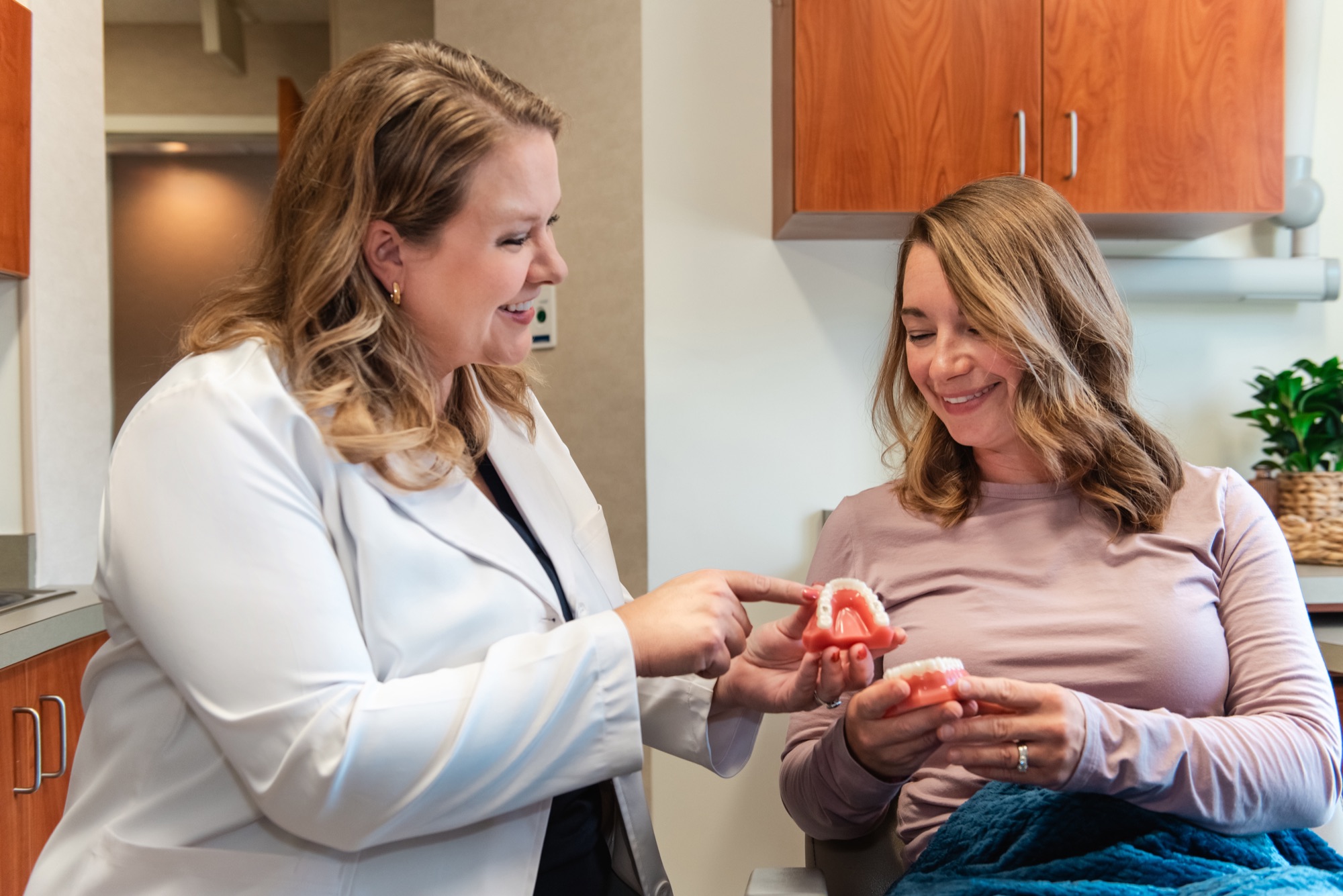 Dr. Julia Lokitis pointing out a detail on a dental model that a patient is holding in the treatment room