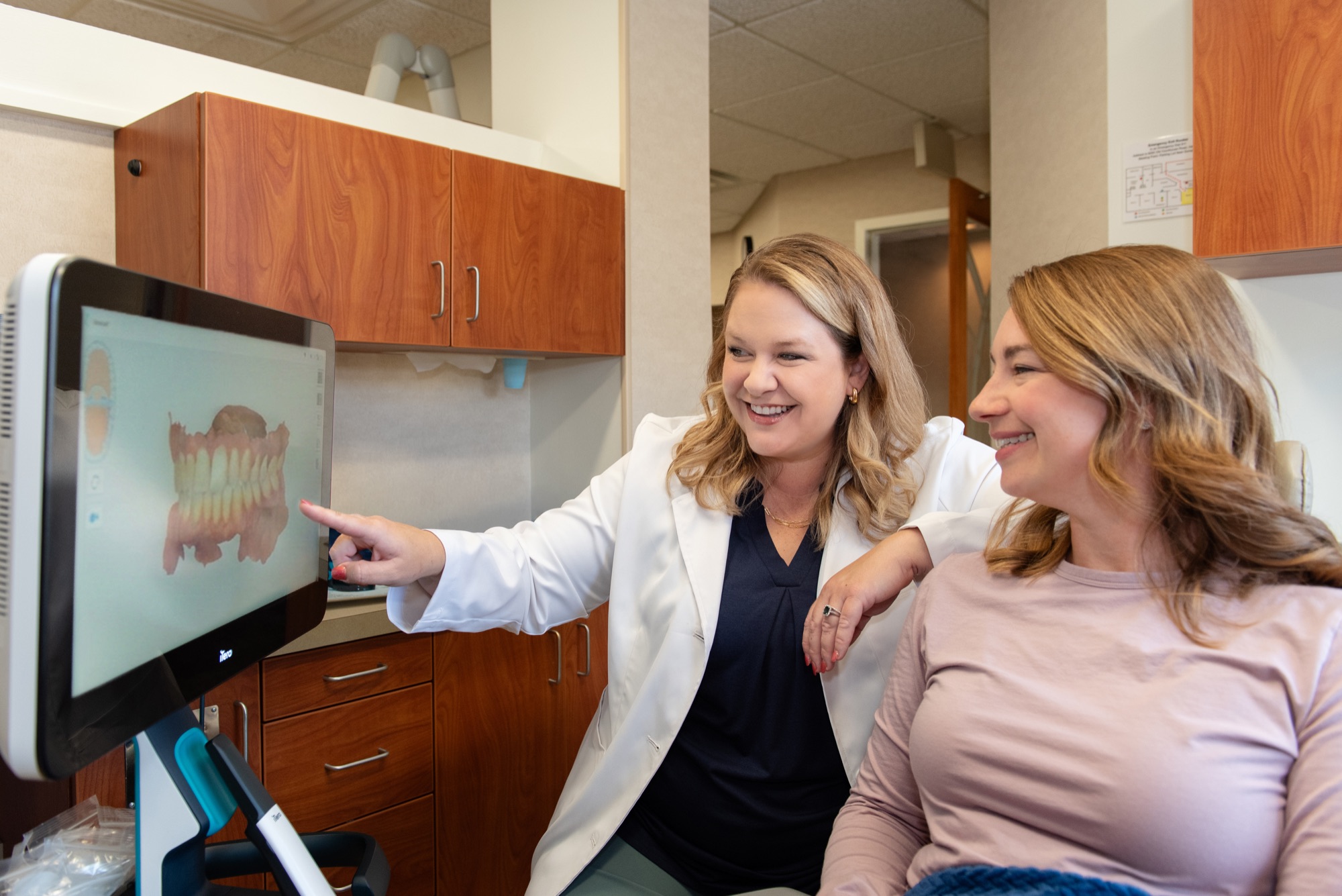 Dr. Julia Lokitis pointing to a 3D scan of a patient's teeth on the chairside screen while the patient looks on