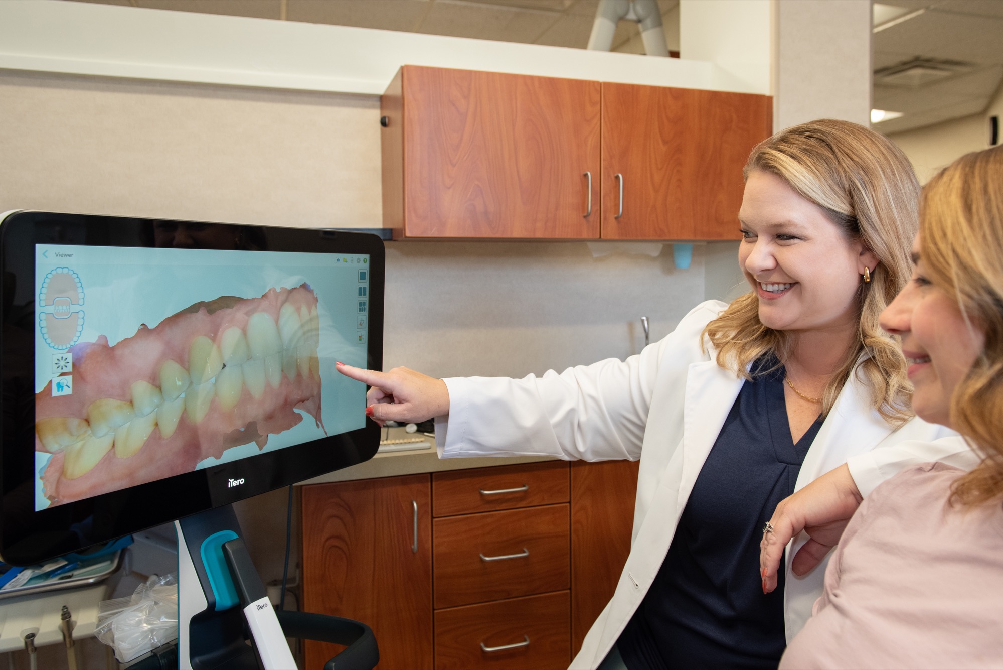 Dr. Julia Lokitis pointing out how a patient's upper and lower teeth meet on a 3D scan shown on the iTero screen beside the chair