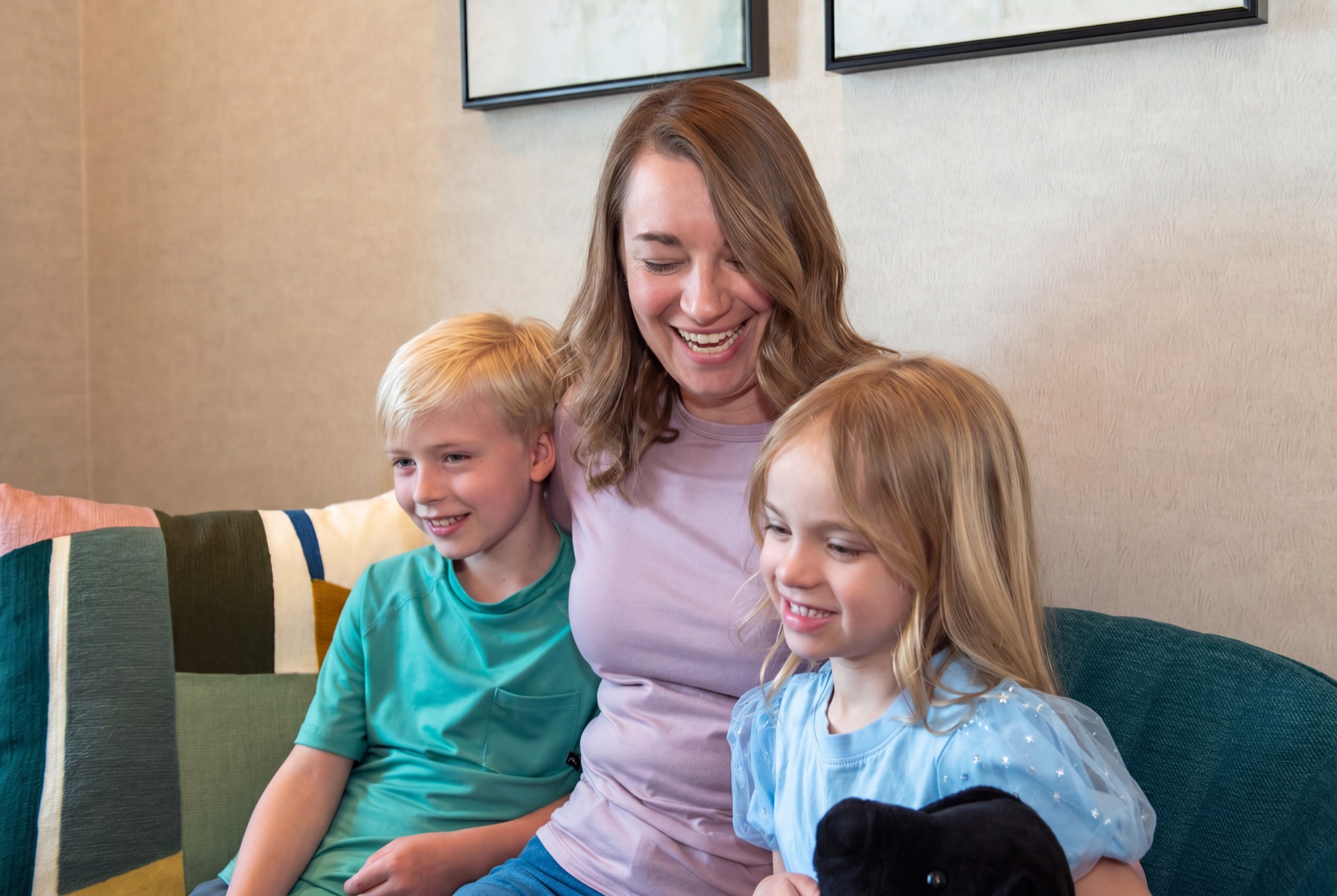A mother and her two children sitting together on the couch in the waiting area