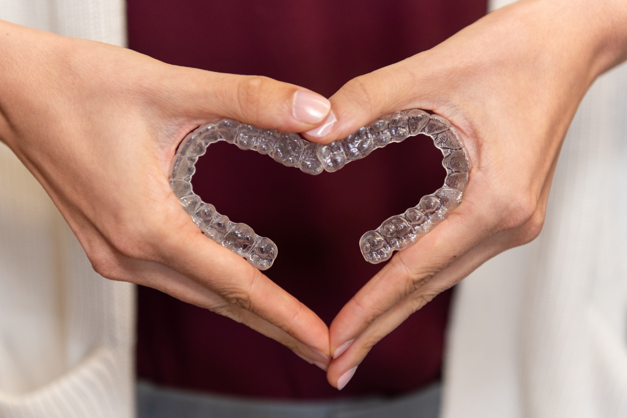 Two clear aligner trays held together to form a heart shape