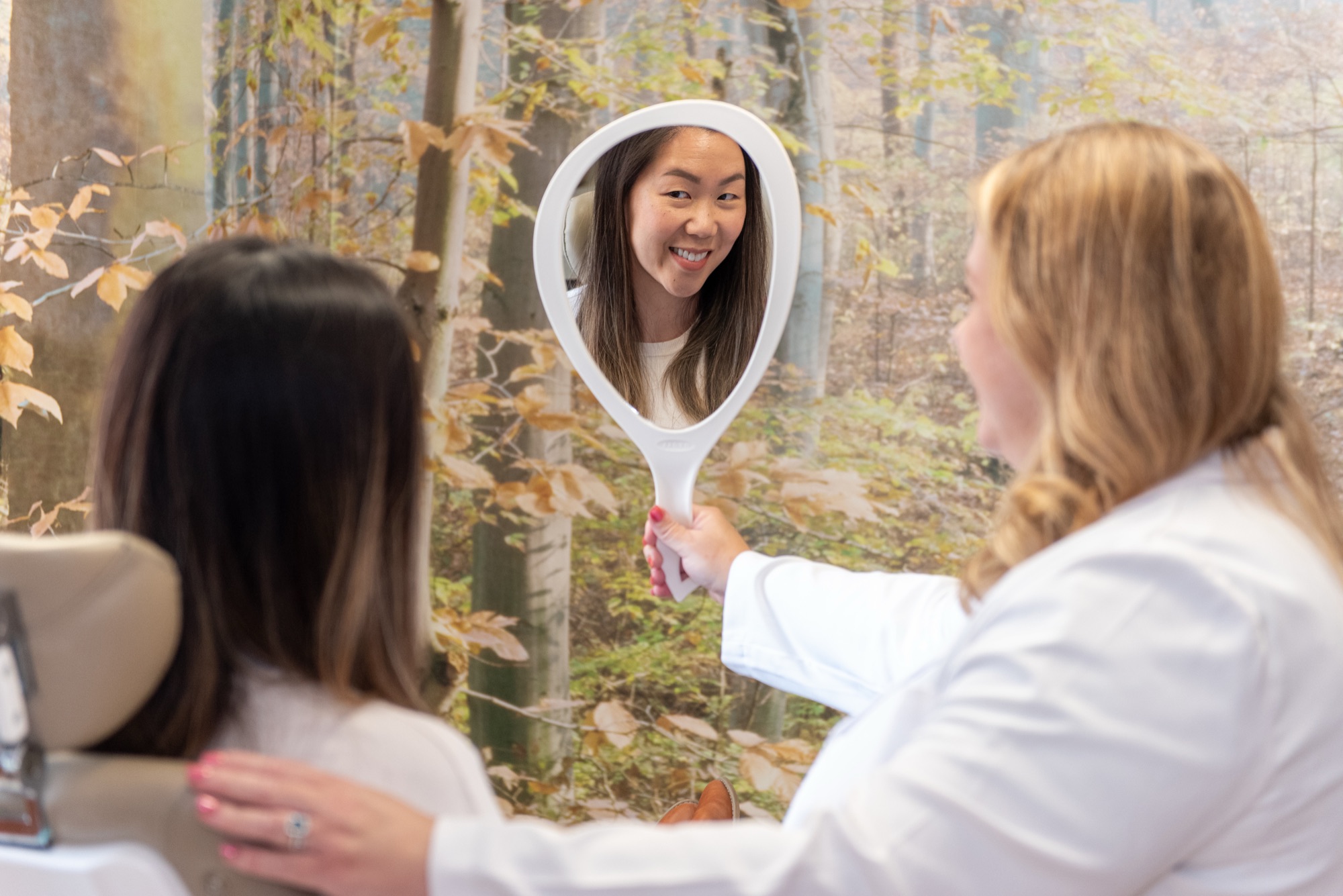 Dr. Julia Lokitis holding a hand mirror so a patient can see her smile at the end of a visit